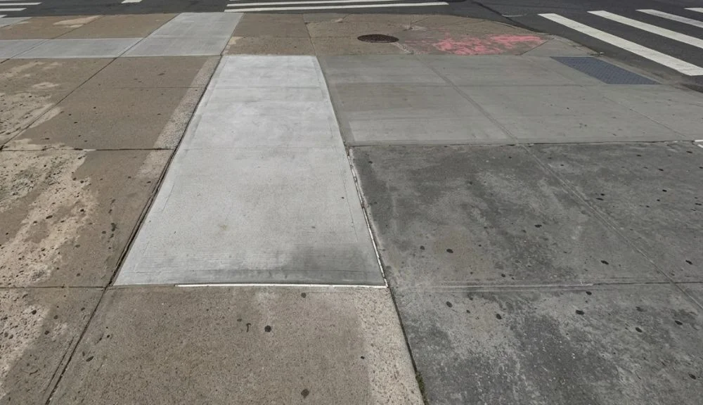 new concrete sidewalk slab beside a harlem crosswalk after dot violation removal